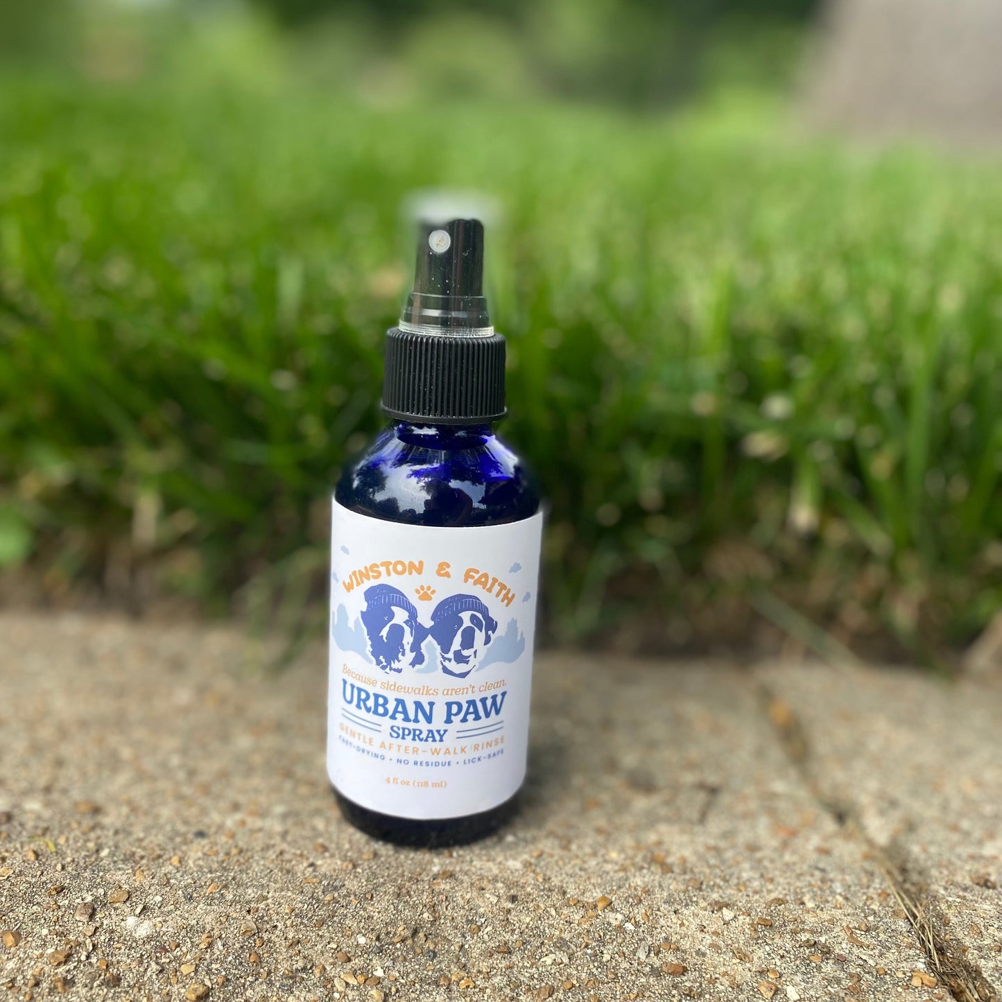 Bottle of Urban Paw spray on a concrete surface with grass in the background