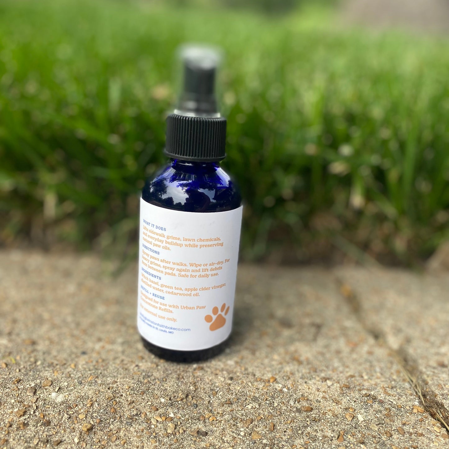 Bottle of pet spray on a concrete surface with grass in the background
